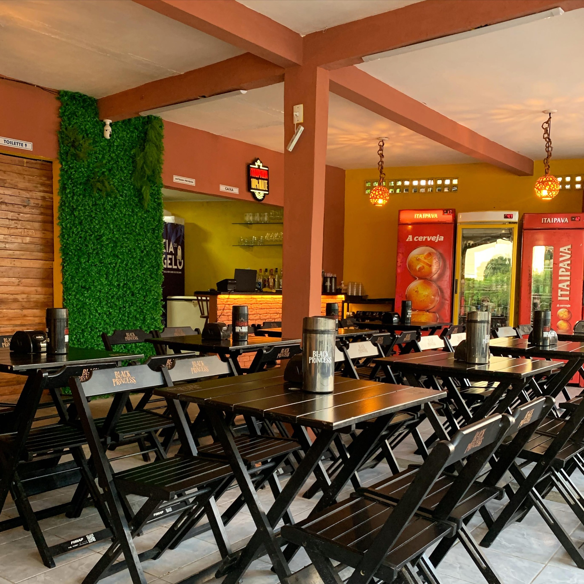 Salão interno do Petrocerva Gastrobar com cadeiras, geladeiras de chopp e decoração